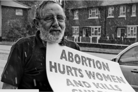 Volunteer holding a pro-life sign in the rain