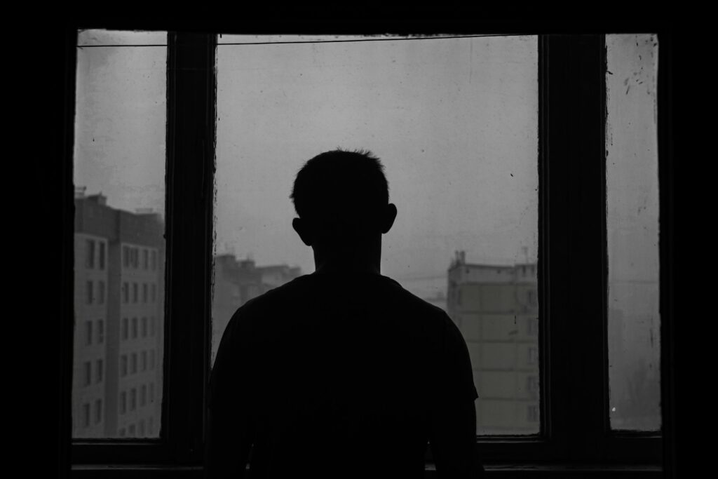 A silhouette of a man looking out of a window.