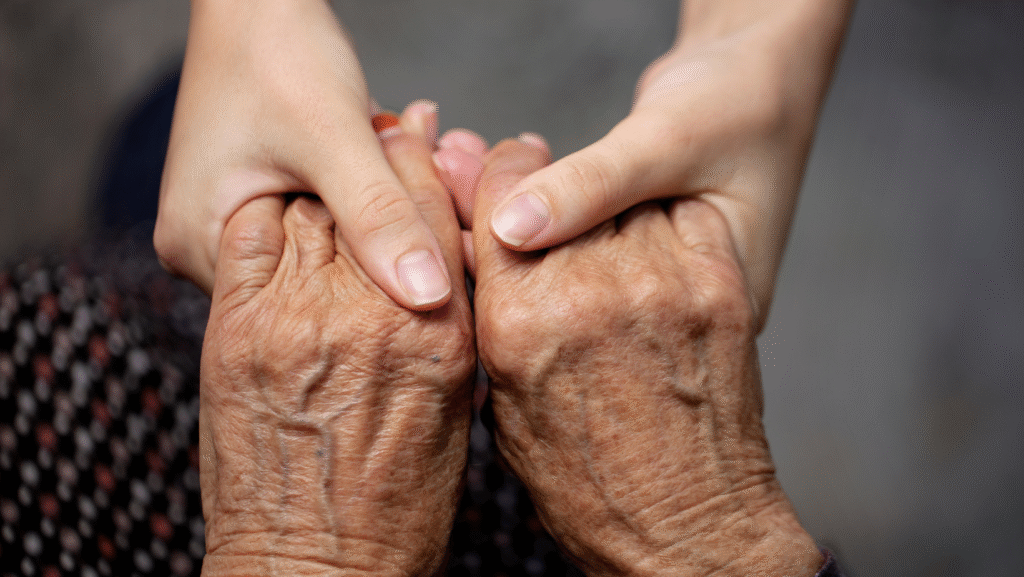 An elderly person holding hands with a younger person