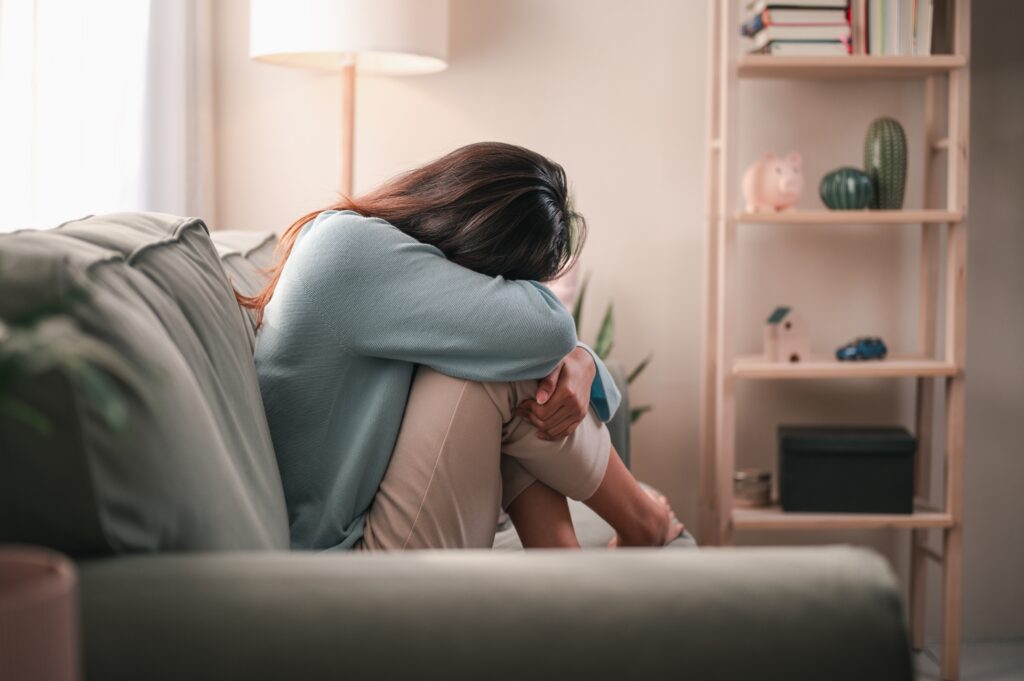 An upset woman sitting on a sofa.