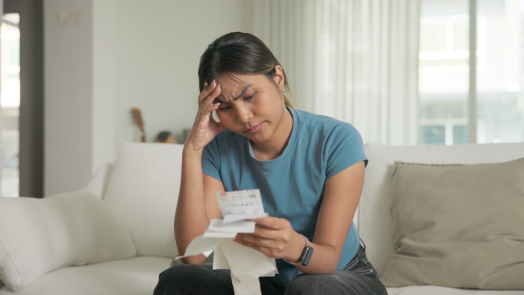 A worried woman looking at receipts in a house
