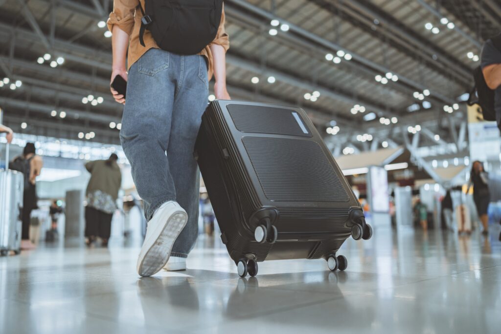 Male,Traveler,Passenger,Walking,With,A,Black,Luggage,At,The
