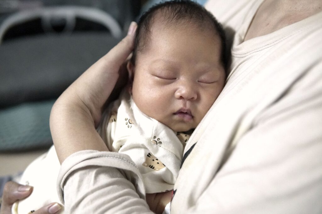 A newborn baby sleeping in the arms of an adult